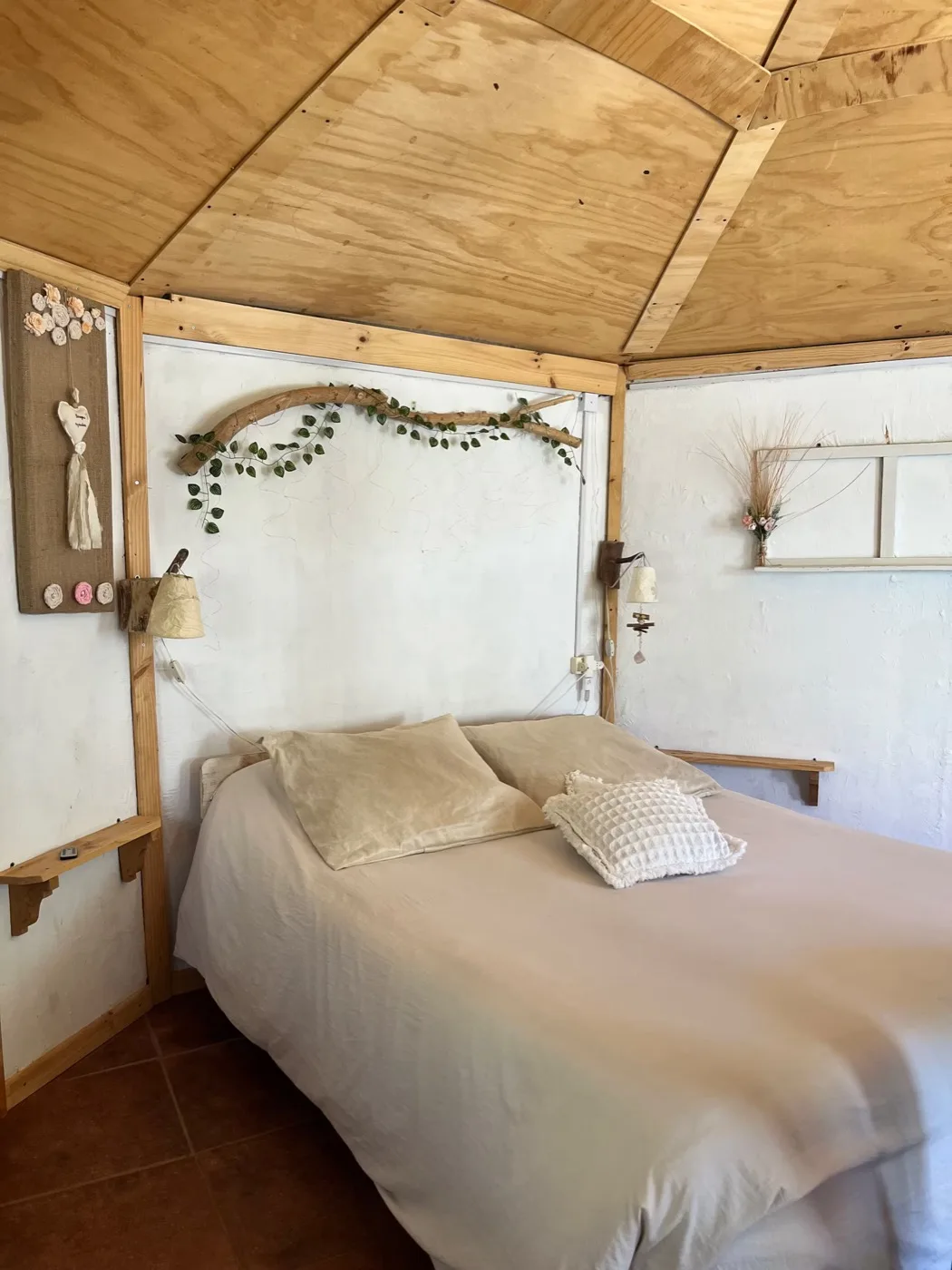 La cama de la cabaña, con la rama de eucalipto sobre el muro