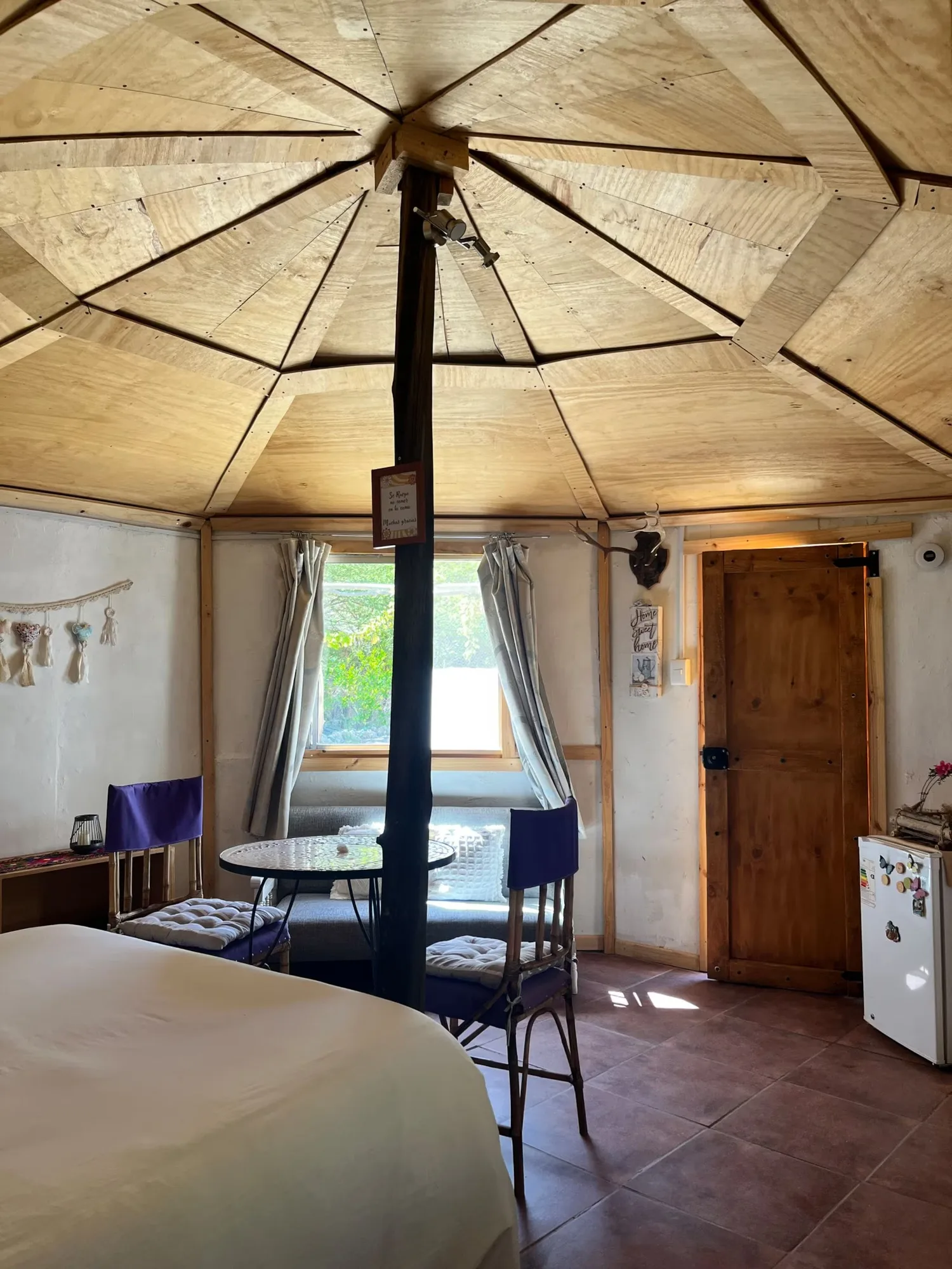 El interior de la cabaña: la cúpula de madera, la cama y la mesa junto a la ventana