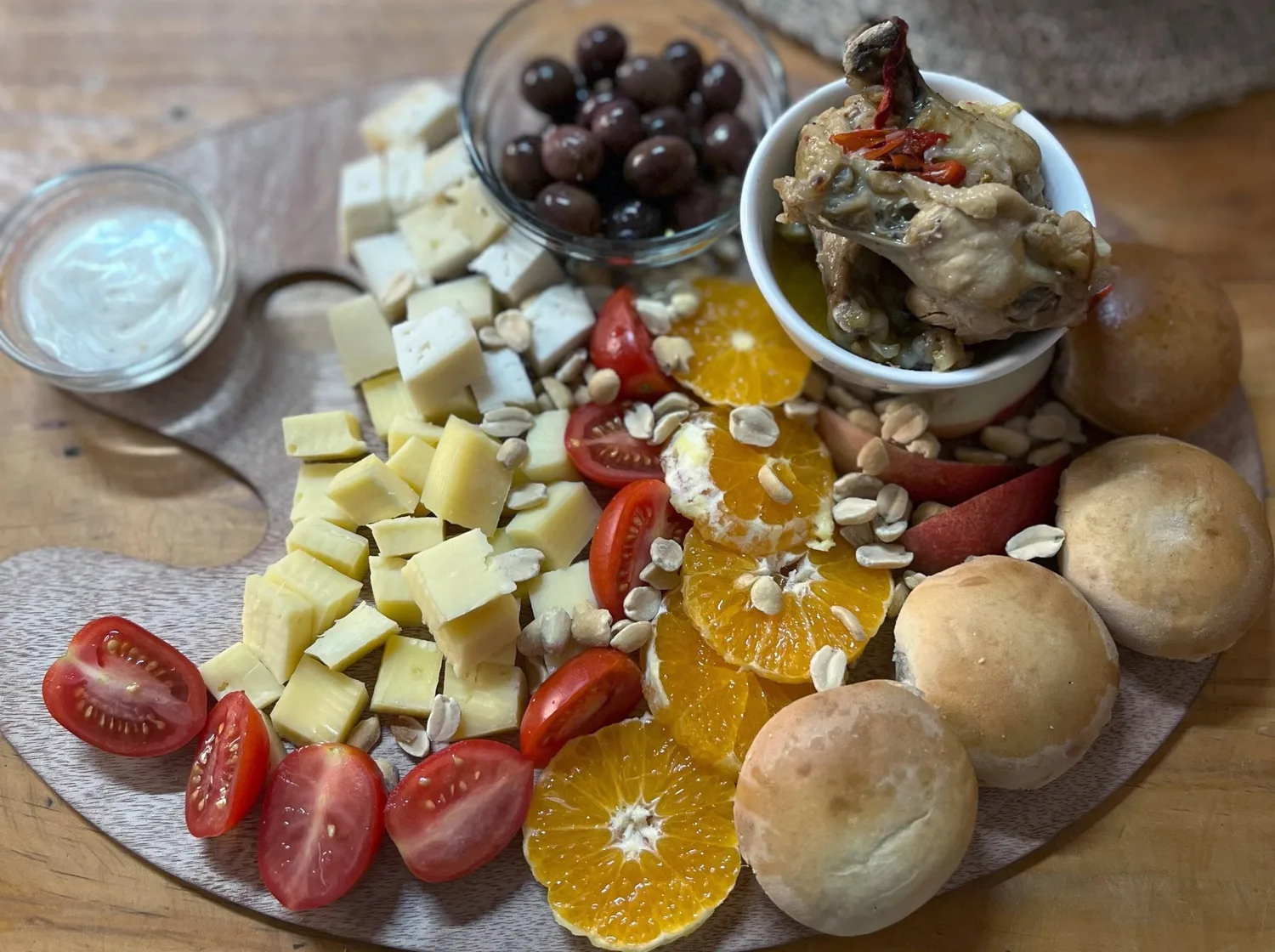 Tabla de quesos con tomates cherry, aceitunas, maní, naranja y pan amasado